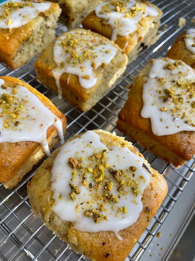 Several rectangular baked goods with white icing and yellow sprinkles on a wire rack.