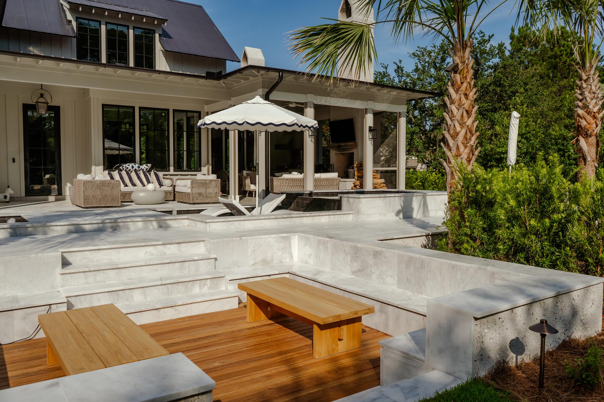 Outdoor patio with seating, umbrella, and wooden benches in a garden setting.