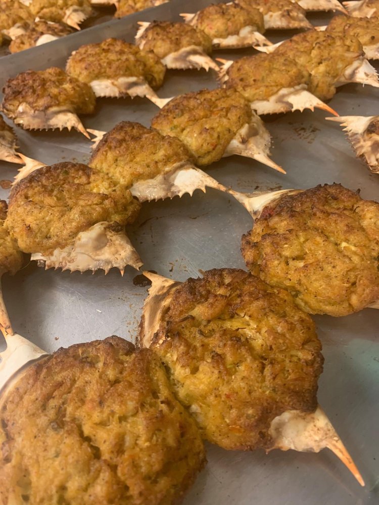 Several cooked chicken drumsticks with breaded coating on a tray, some with exposed bones, arranged in rows.
